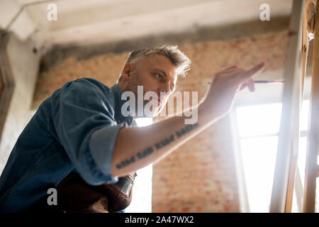 Serious and attentive mid-aged painter working over new painting Stock Photo