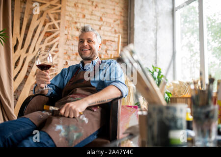 Happy professional artist with glass of wine toasting for success Stock Photo