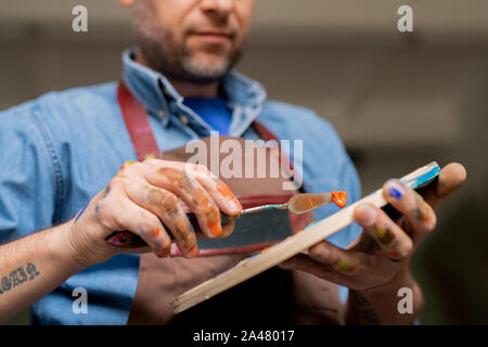 Professional creative painter holding palette while mixing colors or oil paints Stock Photo