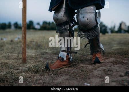 Medieval knight legs in metal armor, back view Stock Photo