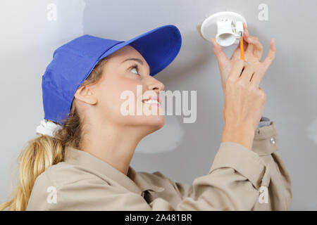 woman installing light fitting Stock Photo