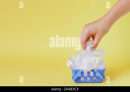 polythene bags in hand in shopping basket on yellow background. Stock Photo