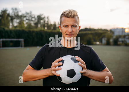 Soccer player holding ball in hands on the field Stock Photo