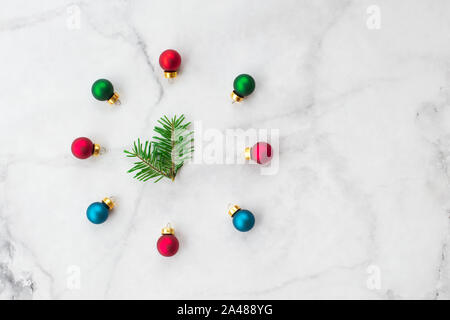 Stylized Christmas clock made of fir-tree branch with blue and red ball toys on marble background. New Year and Christmas celebration concept. Flat la Stock Photo
