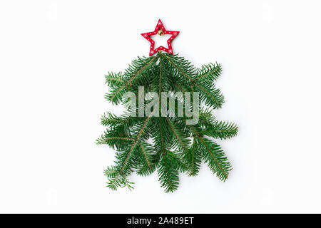 Stylized Christmas tree made of fir tree branches and star toy on white background. New Year and Christmas celebration concept. Flat lay, top view. Stock Photo