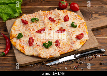 Asian pizza with sun-dried tomatoes, mozzarella and tartar sauce on a bamboo board on a wooden background Stock Photo