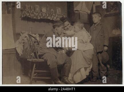 Flash light photo of John Sousa, his mother and some brothers and sisters. John is sitting. Crowded, dirty home. Stock Photo