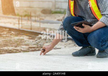 Engineering, wearing a helmet and holding tablets, sitting down To check the structure of the corridor in the park Stock Photo