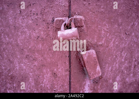 pink glamorous lock hangs on old rusty metal gates with texture cracked paint Stock Photo
