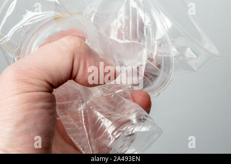 Person holds in his hand several used crumpled transparent plastic cups. Environmental problem concept. Stock Photo