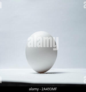 trick with an egg that stands upright on a table on grains of salt Stock Photo
