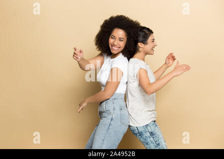 Overjoyed multiracial girlfriends have fun dancing in studio Stock Photo