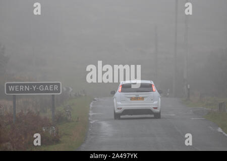 Flintshire, North Wales, UK 13th October 2019. UK Weather:  A deluge of torrential rain will full over the UK with many parts under heavy rain showers and in some places fog.  A motorist travelling along a country lane in the fog and rain in the village of Wern-y-Gaer in Flinthsire © DGDImages/AlamyLiveNews Stock Photo