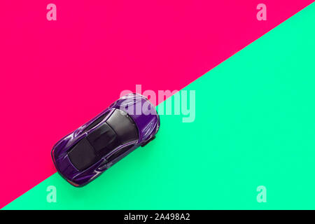 Moscow, Russia - 30 September, 2019. Kids toy car on trendy colorful background. Baby car top view on green and pink colored paper. Boys game. Travel and sport lifestyle. Business, transportation concept Stock Photo