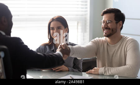 Smiling young man shaking hands with financial advisor. Stock Photo