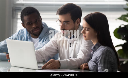 Serious successful team leader working together with mixed race colleagues. Stock Photo
