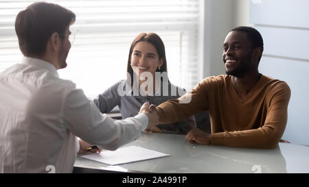 Smiling african american satisfied client shaking hands with salesman. Stock Photo