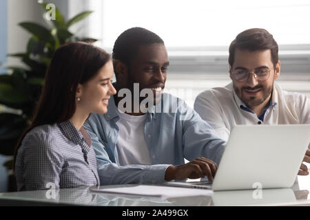 Smiling african american team leader working on computer with colleagues. Stock Photo