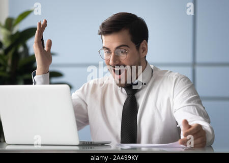 Head shot overjoyed young company worker looking at laptop screen. Stock Photo