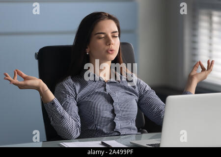 Young female worker making yoga breathing exercises. Stock Photo