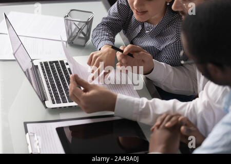 Mixed race young coworkers employees discussing project report. Stock Photo