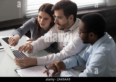 Concentrated millennial diverse colleagues working together on project. Stock Photo