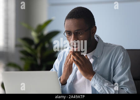 Young african american male intern surprised by received news. Stock Photo