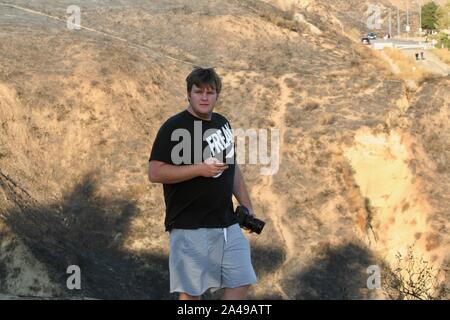 Sylmar, California, USA. 12th Oct, 2019. Stunned Residents assess the damage to their neighborhood at the Porter Ranch Park as they return home as the Sattleridge Fire in the Porter Ranch area of Sylmar, East of Los Angeles, winds down. Santa Ana winds caused a brush fire in the northern foothills of the San Fernando Valley on Oct. 11, burning 7,500 acres, at least 31 structures, including many homes, and forcing thousands to flee. Residents are just returning to their homes today, and gaze at the burnt hillsides surrounding them. Credit: Amy Katz/ZUMA Wire/Alamy Live News Stock Photo