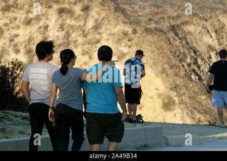 Sylmar, California, USA. 12th Oct, 2019. Stunned Residents assess the damage to their neighborhood at the Porter Ranch Park as they return home as the Sattleridge Fire in the Porter Ranch area of Sylmar, East of Los Angeles, winds down. Santa Ana winds caused a brush fire in the northern foothills of the San Fernando Valley on Oct. 11, burning 7,500 acres, at least 31 structures, including many homes, and forcing thousands to flee. Residents are just returning to their homes today, and gaze at the burnt hillsides surrounding them. Credit: Amy Katz/ZUMA Wire/Alamy Live News Stock Photo
