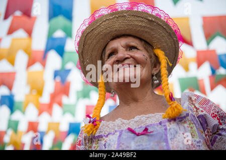 Caruaru, Pernambuco, Brazil - July 11, 2016: Woman with traditional clothing under colorful pennants during the celebration of Brazilian June parties Stock Photo