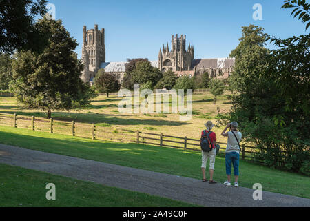 Walking UK summer, rear view in summer of two middle aged walkers looking at the cathedral skyline of the city of Ely in Cambridgeshire, England, UK. Stock Photo