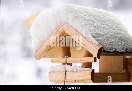 Snow covered wooden birdfeeder in winter. Stock Photo