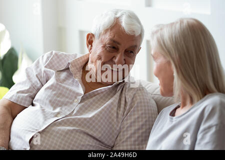 80s man sitting on couch talking with middle aged woman Stock Photo