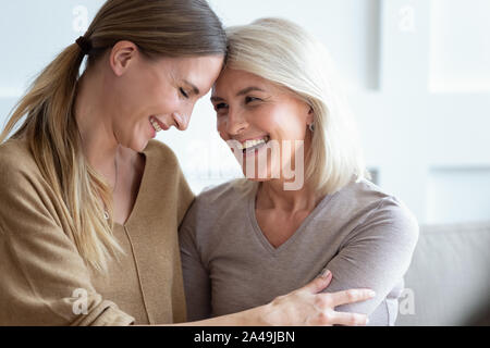 Closeup image aged mother and adult daughter touch foreheads laughing Stock Photo