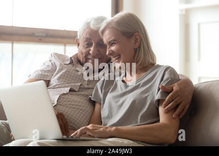 Old husband and wife using laptop chatting with grownup children Stock Photo