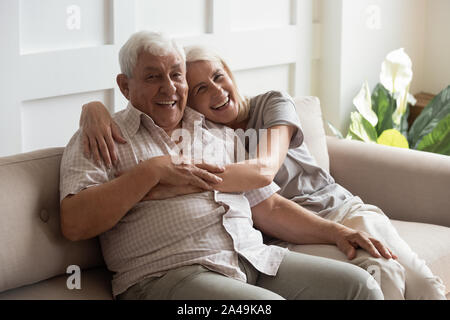 Happy mature couple resting on couch looking at camera Stock Photo
