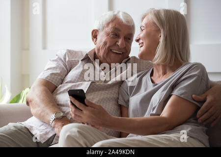 Elderly husband and middle-aged wife having fun using smartphone Stock Photo