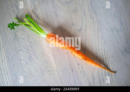 Lonely fresh raw carrots with odkusannymi pieces lying on a wooden kitchen table. Top view. Close-up. Stock Photo