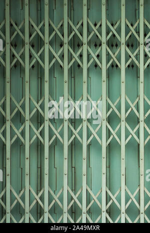 Folding old green metal door gate. Expanded metal sliding gate. Old style grunge metal door. Rustic expanded metal shutter door close with lock pad. Stock Photo