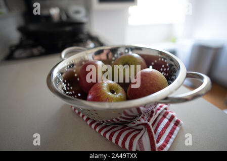 London, United Kingdom - September 15, 2019: British apples sit in a collander after being washed in the kitchen. Stock Photo