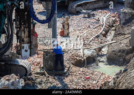 Workers and rotary drilling machine heavy equipment  for deep foundation piles at construction site. Stock Photo