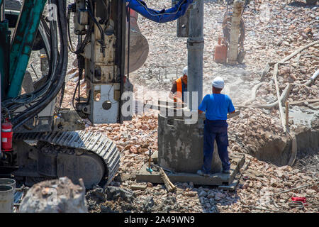 Workers on a rotary drilling machine heavy equipment for deep foundation piles at construction site. Stock Photo