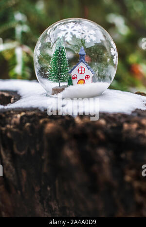 Transparent cristalball with christmas tree and house inside. Snow in christmas ball. Stock Photo