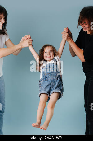 Two women swinging toddler girl holding her hands Stock Photo