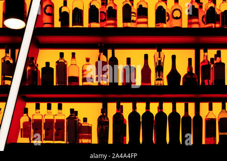 Bottles sitting on shelf in a bar, red neon blacklight Stock Photo