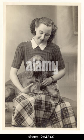 Early 1900's studio portrait of young woman / teenage girl wearing a short sleeved knitted jumper, with a pet cocker  spaniel, circa 1937, U.K. Stock Photo