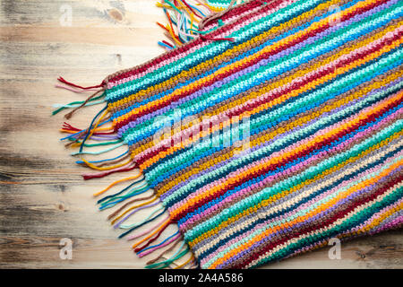 Hand made knitted multicolored plaid on a wooden background. Top view. Stock Photo