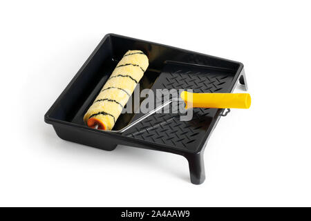 Paint roller with a yellow handle in a black cuvette. Close-up. Isolated over white background. Stock Photo