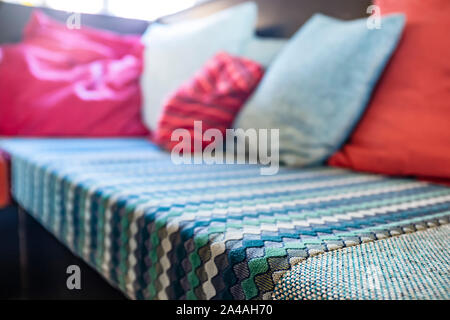 Soft, comfortable sofa is covered with a beautiful bedspread and with pillows of different colors. Interior and comfort in the house. Close-up. Stock Photo