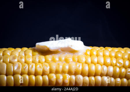 Hot Sweetcorn on the cob with butter melting over it with a dark background Stock Photo